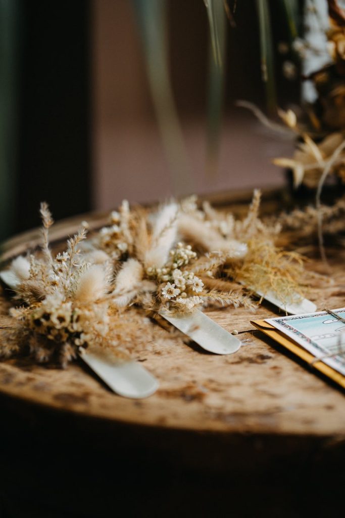 In questa foto tre corsage per damigelle di nozze realizzati con fiori secchi e stabilizzati di colore bianco panna