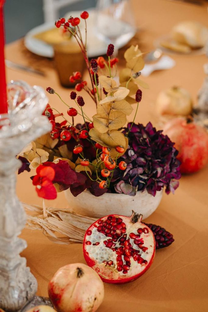 In questa foto un dettaglio della mise en place del matrimonio di Tamara ed Enzo realizzata da NoidueWedding nei toni del rosso e del senapce con ortensie, bacche e melograni