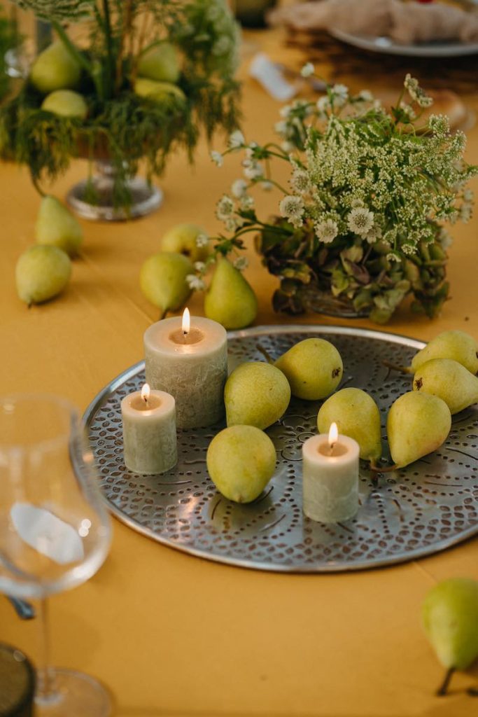 In questa foto un dettaglio di mise en place di nozze realizzato da NoidueWedding con candele di colore verde, foliage e pere