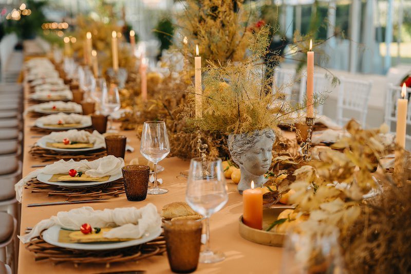 In questa foto un tavolo allestito da NoidueWedding per il matrimonio di Tamara ed Enzo nei toni del senape con arbusti, candele e terracotte