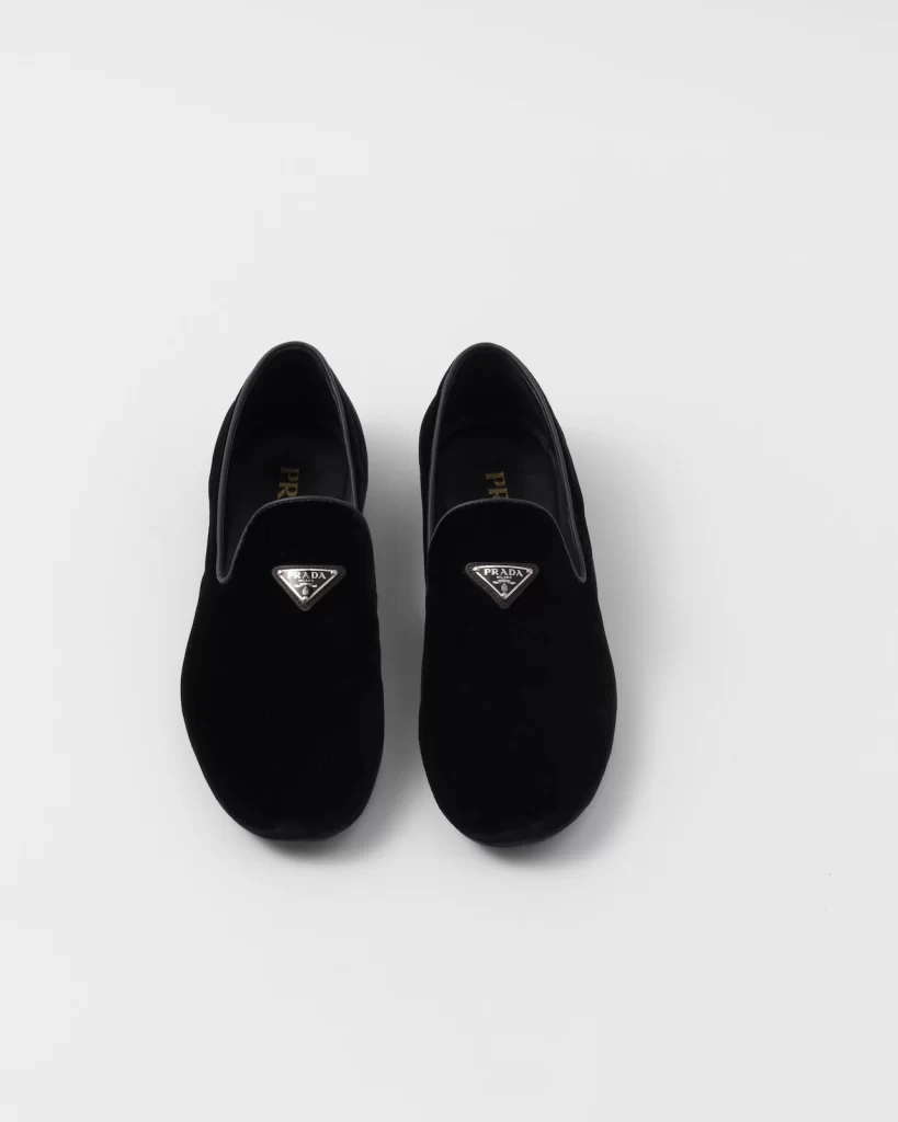 In questa foto scarpe sposo a pantofola nere di velluto Prada 2024.