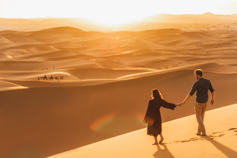 In questa foto una coppia si tiene per mano tra le dune del Wahiba Sands, il deserto dell'Oman, tra le mete per viaggi di nozze originali