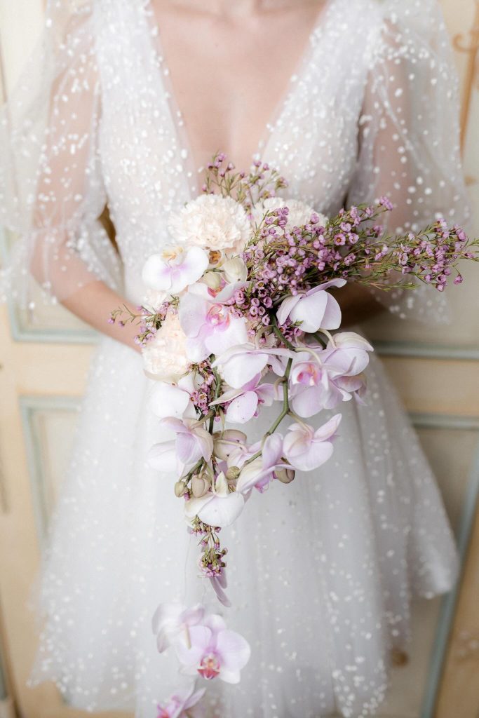 In questa immagine un bouquet sposa con orchidee rosa e fiori bianchi. 