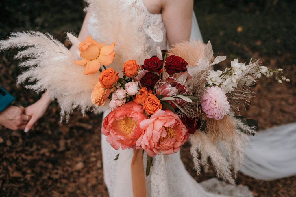 In questa immagine un bouquet sposa nelle tonalità della'rancio e del rosso. 
