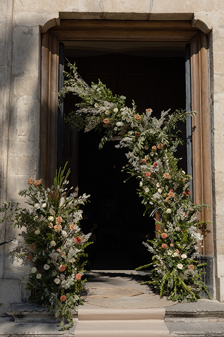 In questa foto una composizione floreale di fiori e foglie davanti la chiesa