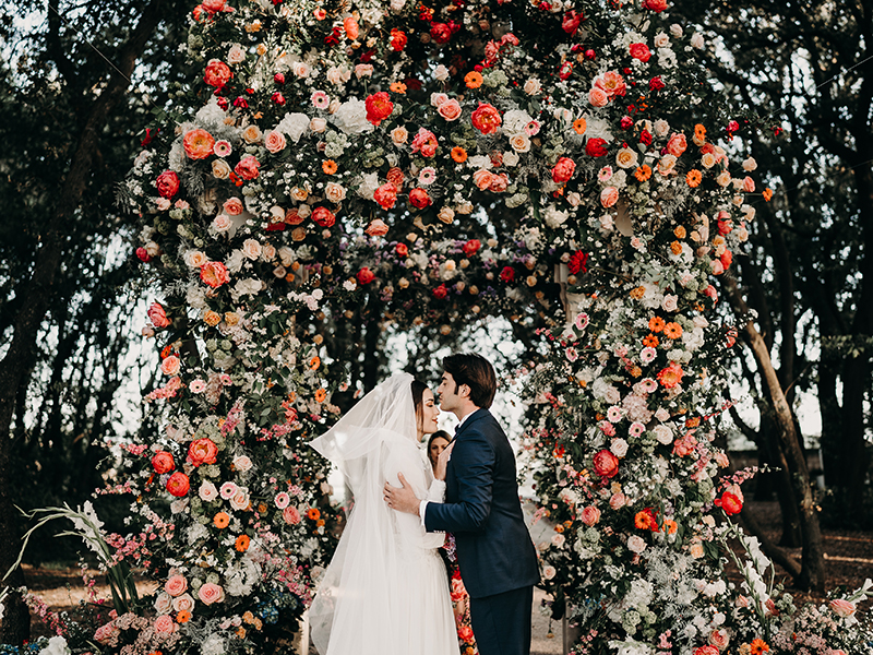 In questa foto due sposi sotto rose fiori matrimonio 2024