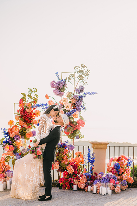 In questa foto due sposi con un arco di fiori colorato