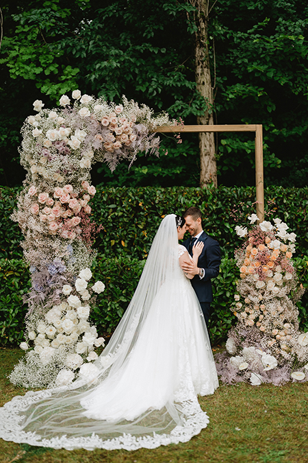 In questa foto due sposi con un arco rettangolare con fiori