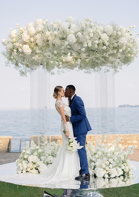 In questa foto due sposi circondati da fiori bianchi