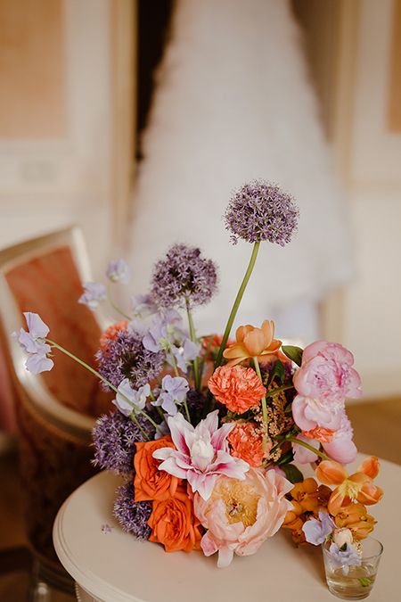 In questa foto un centrotavola con fiori di matrimonio arancioni e lilla