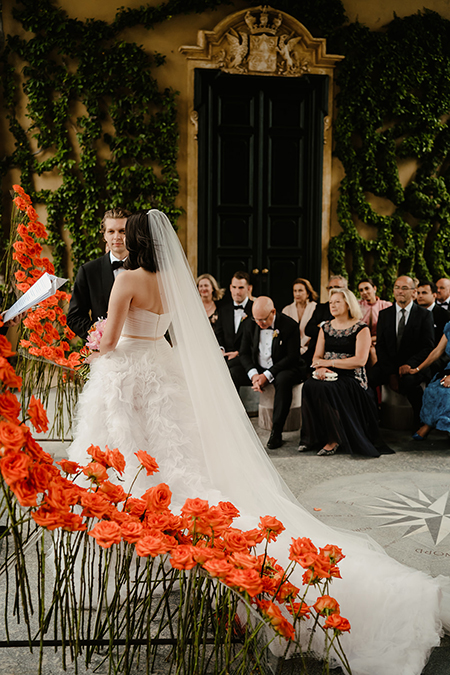 In questa foto due sposi all'altare con fiori di matrimonio rose arancioni