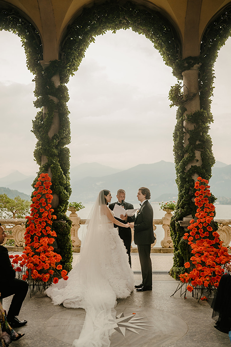 In questa foto due sposi all'altare con fiori di matrimonio rose arancioni