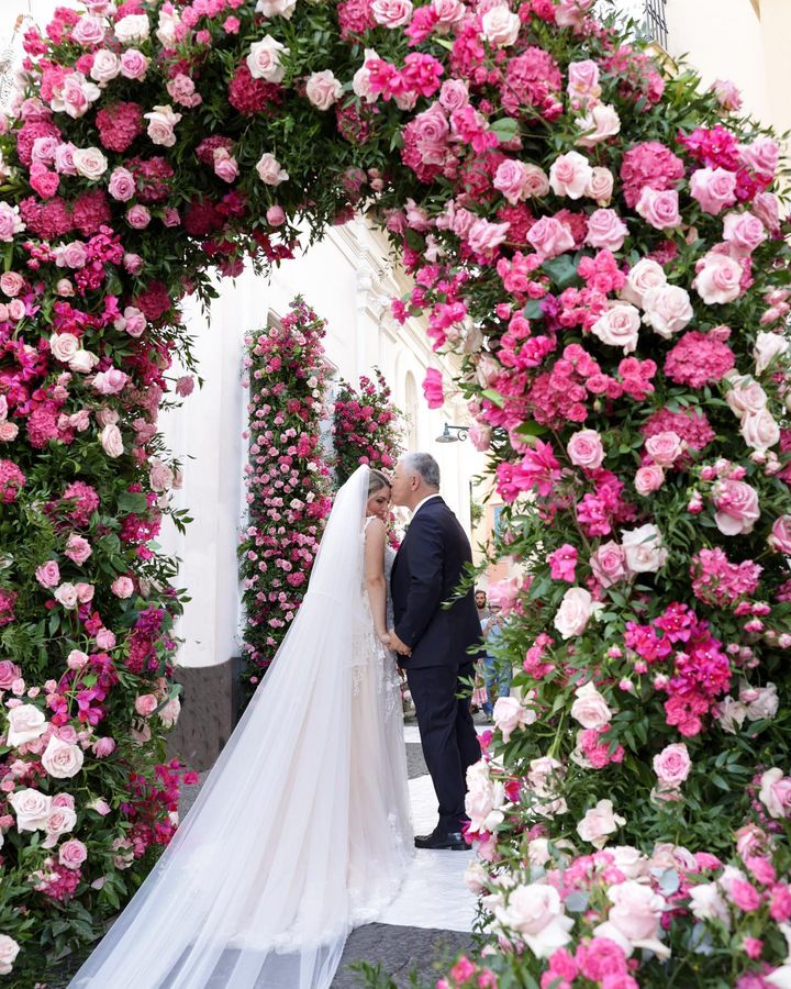 In questa foto un allestimento floreale di matrimonio 2024 con arco di rose fuxia e rosa 