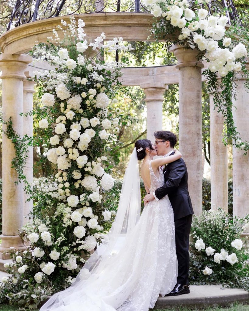 In questa foto due sposi con un arco di rose bianche