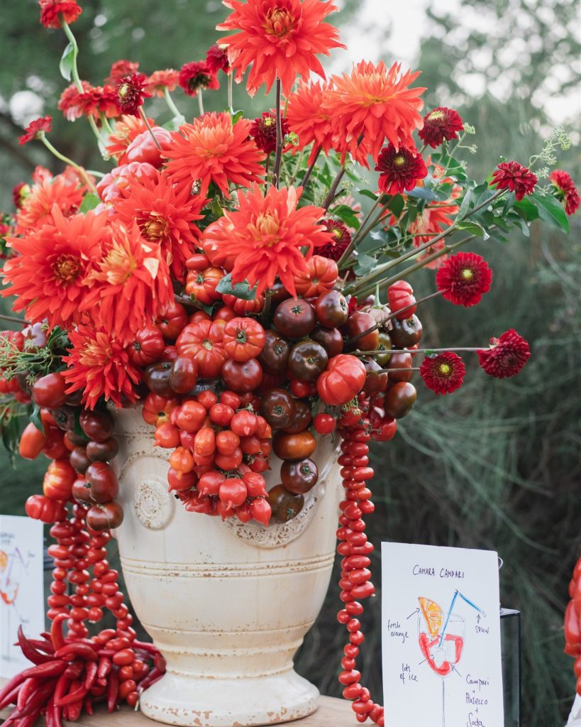 In questa foto una composizione floreale di matrimonio con fiori rossi e pomodori