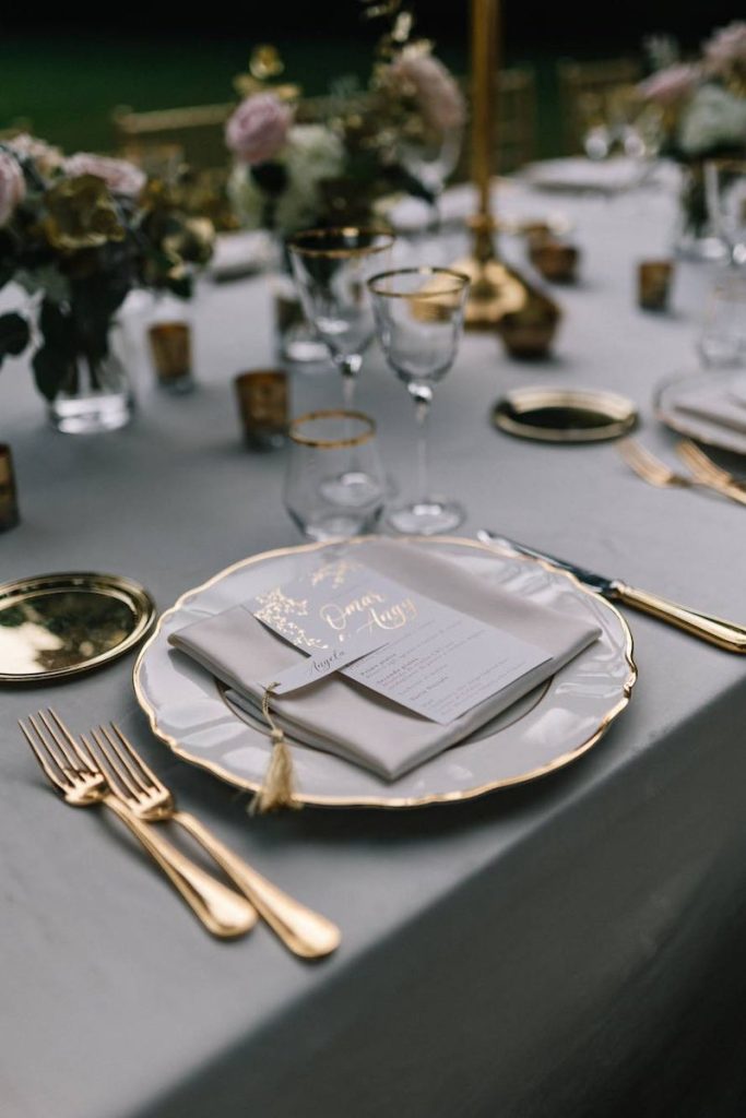 In questa foto il dettaglio di una mise en place elegante con posate dorate e piatti in porcellana con bordo oro