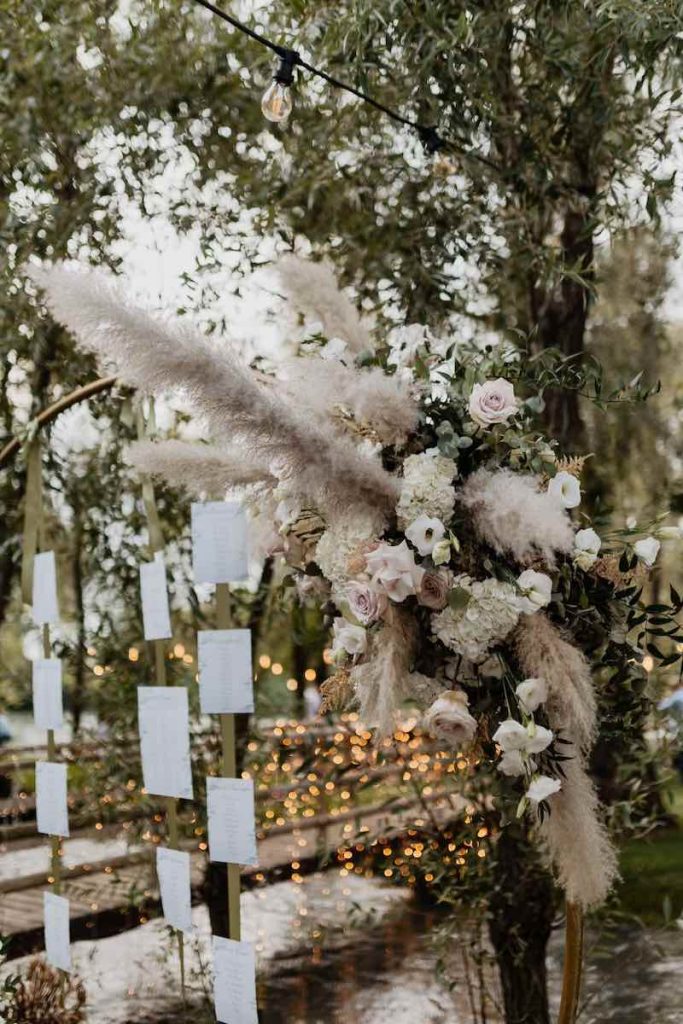 In questa foto un tableau de mariage decorato con rose di colore rosa e pampas