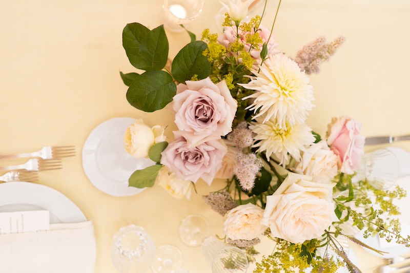 In questa foto un centrotavola di rose e peonie inquadrato dall'alto sulla tavola del matrimonio progettato da Benedetta Carpanzano per Roberta e Domenico