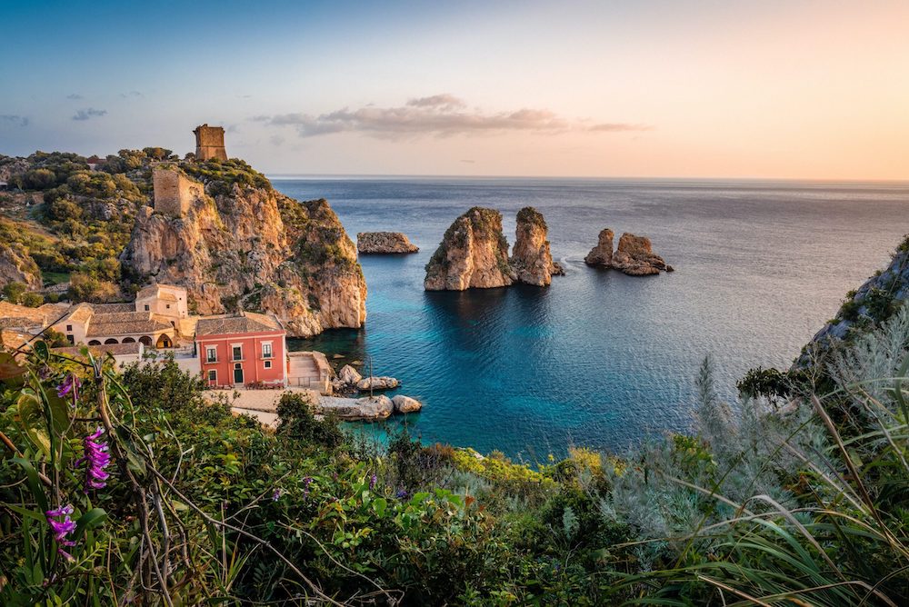 In questa foto una veduta aerea della Tonnara di Scopello e dei faraglioni che sorgono nel tratto di mare di fronte ad essa: la location siciliana è tra le Destination Wedding Venues in Italia più amate dalle coppie straniere 