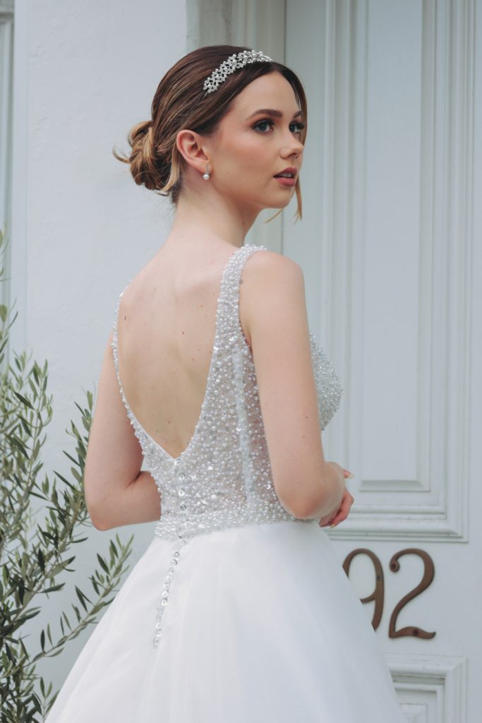 In questa immagine un abito da sposa con corpetto ricoperto interamente da perle e dettagli che brillano. 