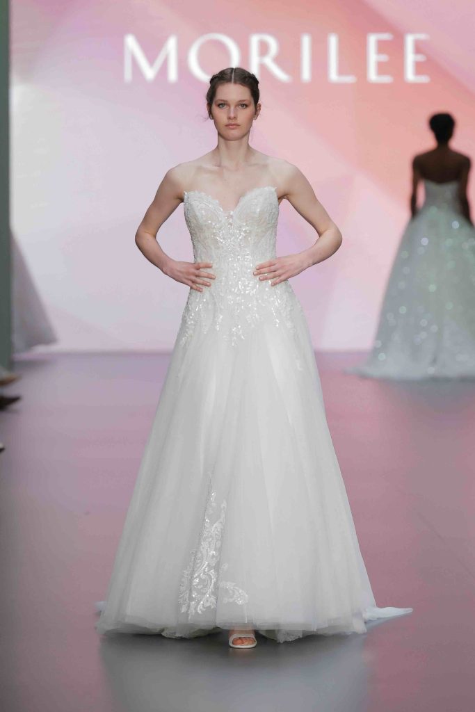 In questa immagine un abito da sposa Morilee 2025 con dettagli floreali.