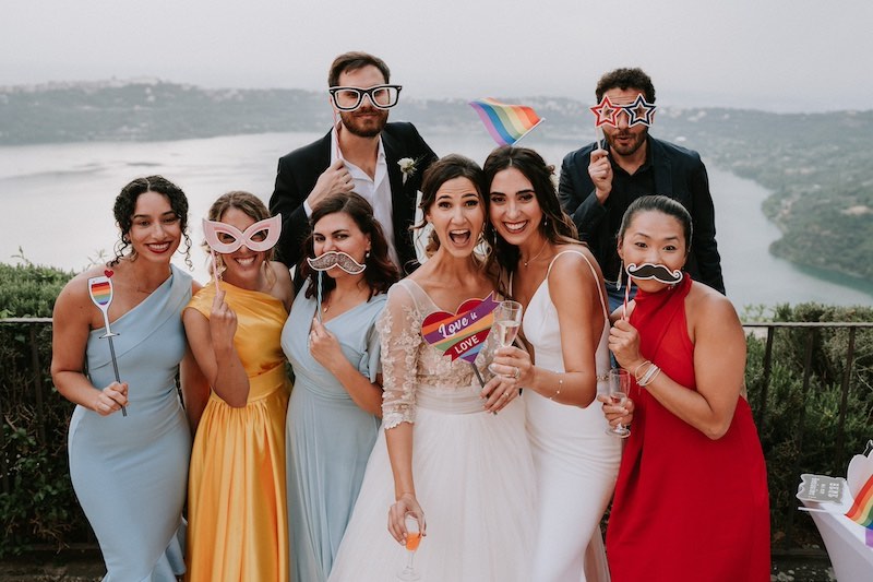 In questa foto di Emiliano Allegrezza, due spose posano per uno scatto divertente con i loro amici che indossano props