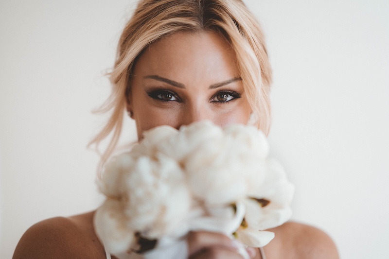 In questa foto di Emiliano Allegrezza, una sposa posa dietro al suo bouquet di fiori bianchi