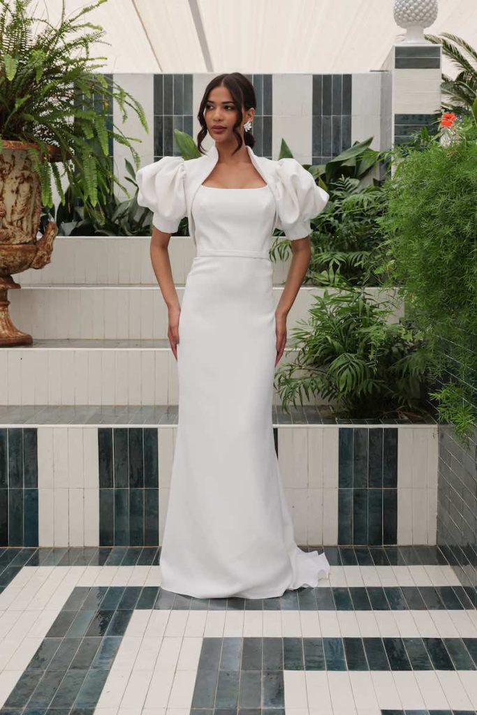 In questa foto una modella indossa un abito da sposa a sirena con scollatura quadrata abbinato ad un bolero con maniche balloon 