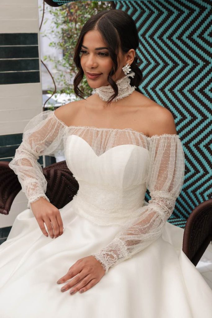 In questa foto una modella indossa un abito da sposa abbinato da un cappa con maniche balloon e ad un choker in pizzo 