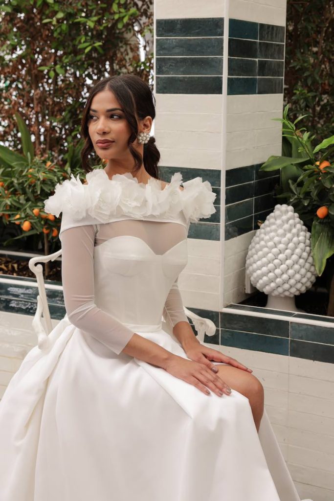 In questa foto una modella indossa un abito ad A con scollo a cuore e coprispalle a maniche lunghe in tulle e fiori 3D 