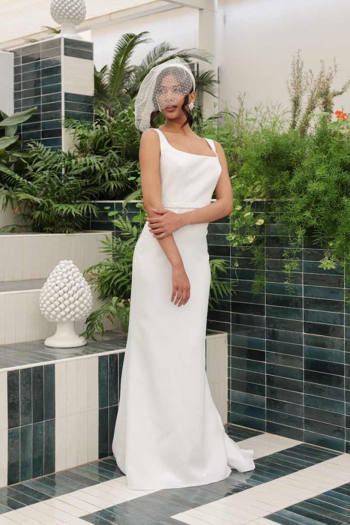 In questa foto una modella indossa un abito da sposa a sirena con scollo quadrato abbinato ad una veletta in tulle 