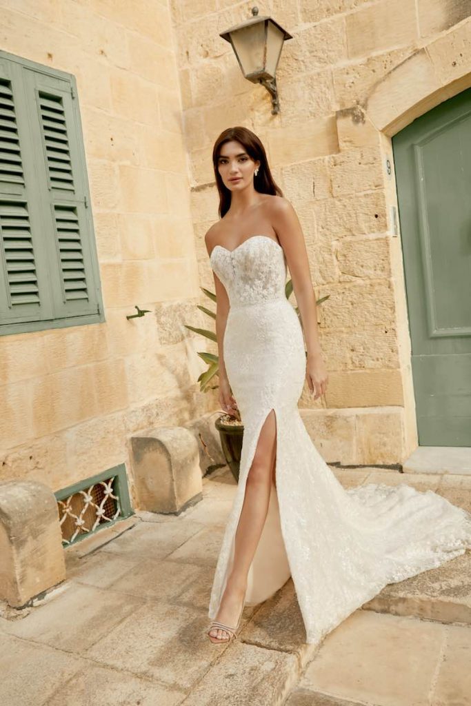 In questa foto una modella indossa un abito da sposa a sirena in pizzo floreale con spacco laterale, scollo a cuore 