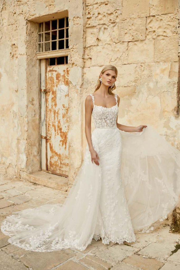 In questa foto una modella indossa un abito da sposa a sirena in pizzo floreale con sopragonna staccabile