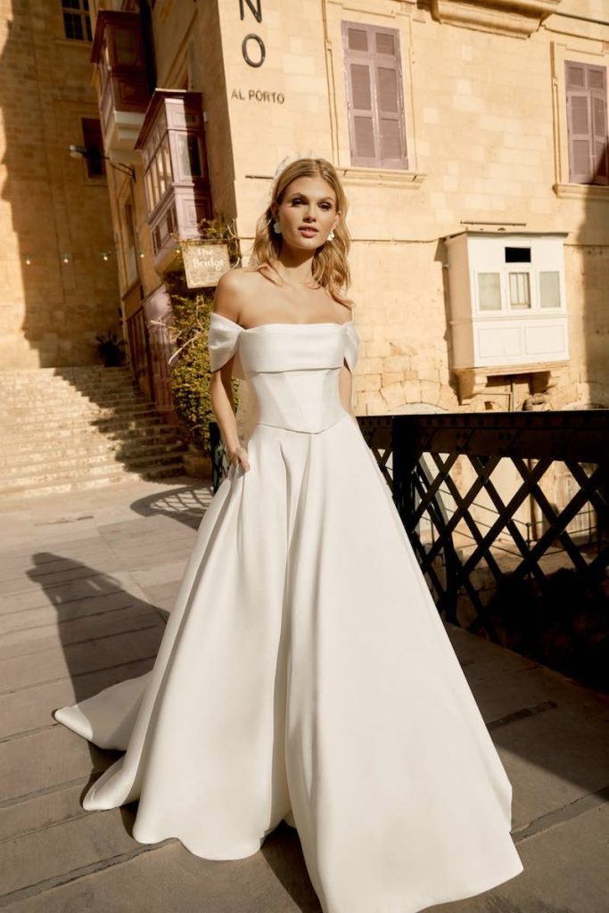 In questa foto una modella indossa un abito da sposa in mikado e corpetto steccato della collezione Sincerity Bridal Primavera Estate 2025