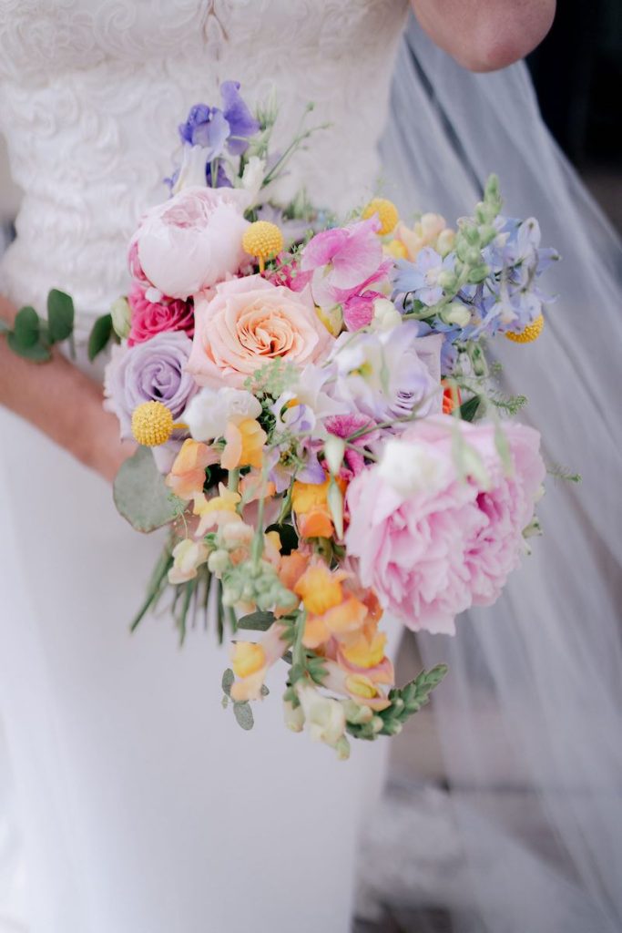 In questa foto, un bouquet da sposa 2025 nei toni del rosa, del lilla e del giallo