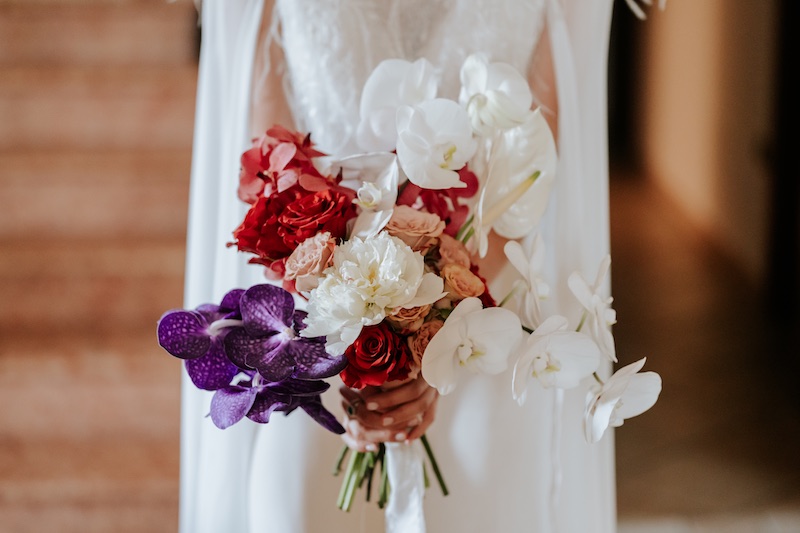In questa foto, un bouquet nei toni del rosso, del viola e del bianco