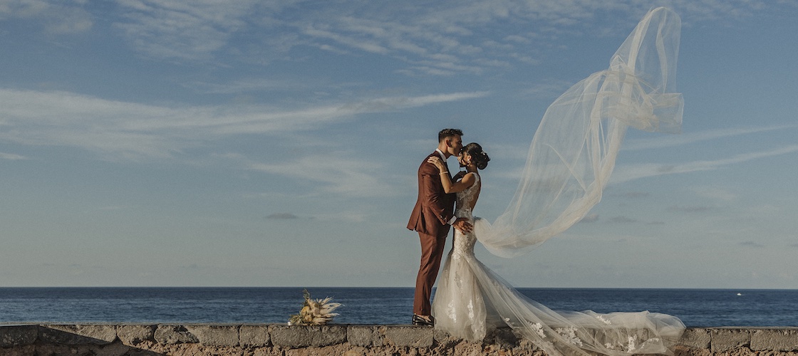 In questa foto di Salvatore Cimino, due sposi in riva al mare che si baciano mentre il velo della sposa è sollevato dal vento
