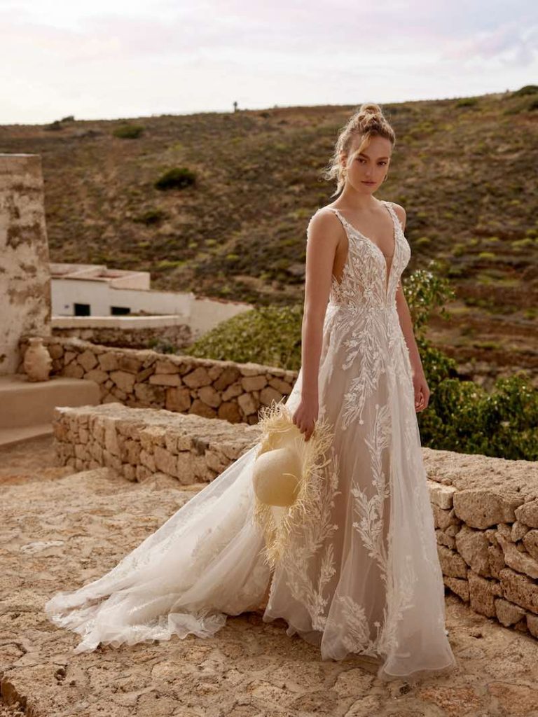 In questa foto, una modella indossa un abito scivolato ramage floreale della collezione sposa Lilian West SS 2025