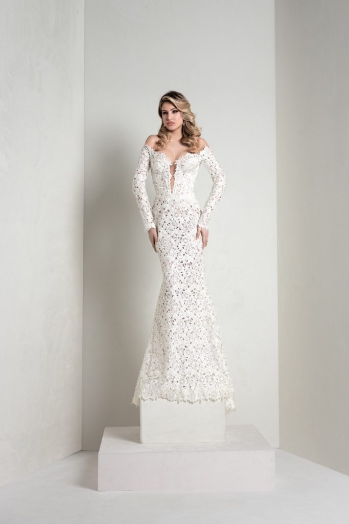 In questa foto, una modella indossa un abito della collezione sposa Markisa 2026 a sirena in pizzo macramè con maniche lunghe e scollo a cuore