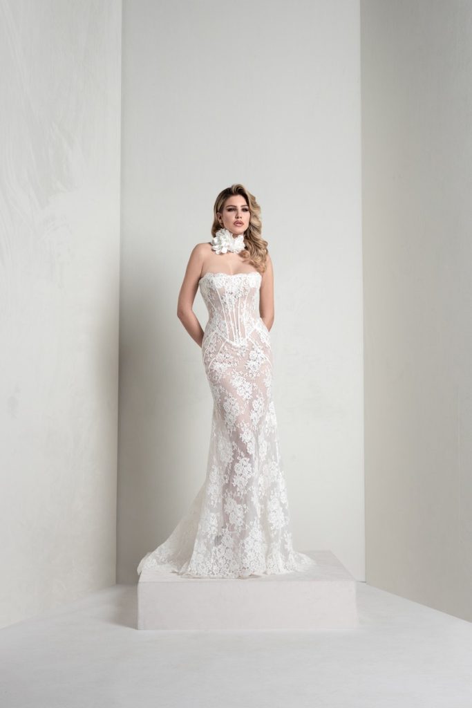 In questa foto, una modella indossa un abito della collezione sposa Markisa 2026 a sirena in pizzo con bustier steccato e choker floreale
