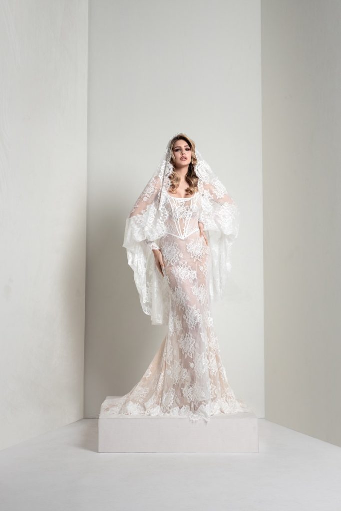 In questa foto, una modella indossa un abito della collezione sposa Markisa 2026 a sirena in pizzo e velo a mantiglia abbinato