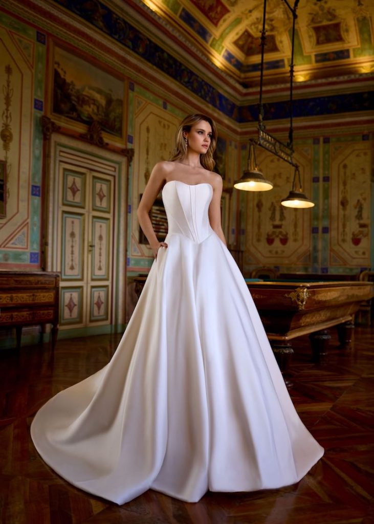 In questa foto, una modella indossa un abito da sposa ampio con corpetto a vita basca
