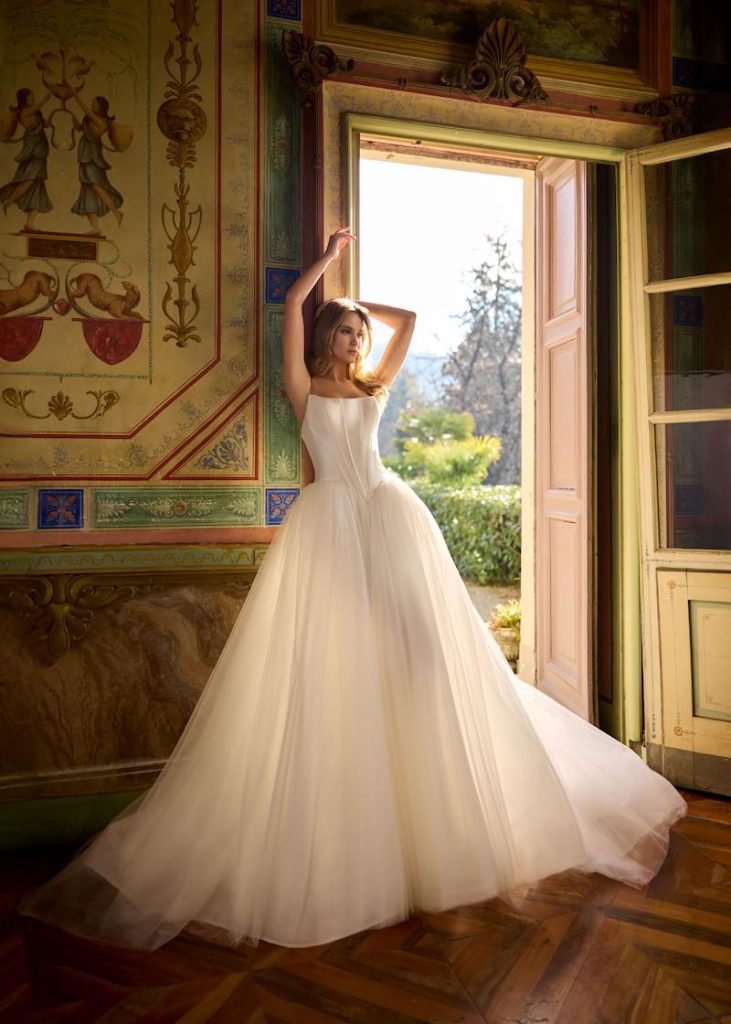 In questa foto, una modella indossa un abito da sposa ampio con corpetto a vita basca
