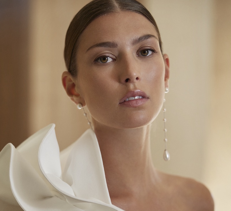 In questa foto, una modella indossa un abito da sposa Rosa Clarà e un trucco sposa naturale che punta l'attenzione sulle labbra dipinte con un rossetto luminoso