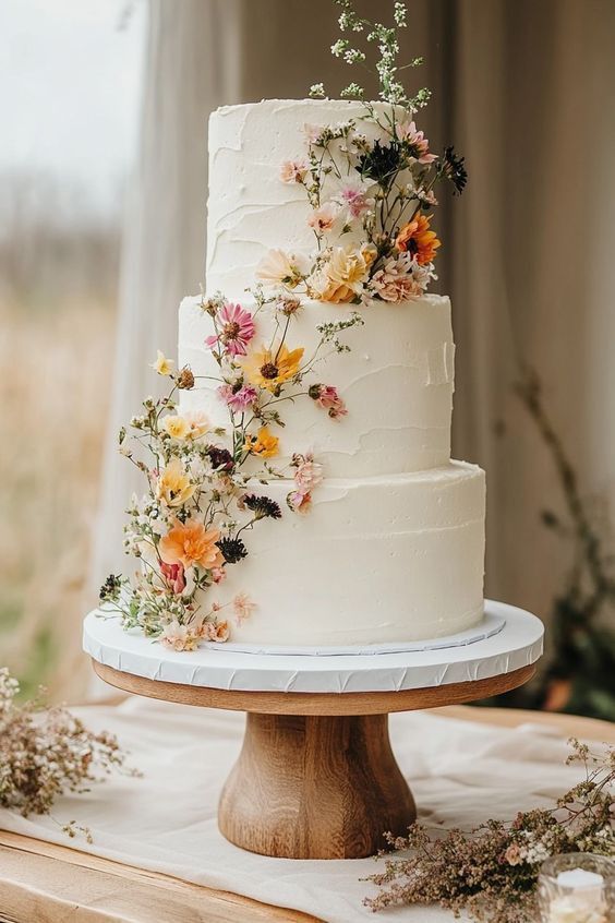 In questa foto una torta nuziale multipiano decorata con fiori di veri e coloratissimi