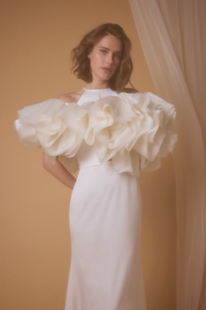 In questa foto, una modella che indossa un abito da sposa scivolato in satin triacetato con bolero della collezione sposa Nagae 2026