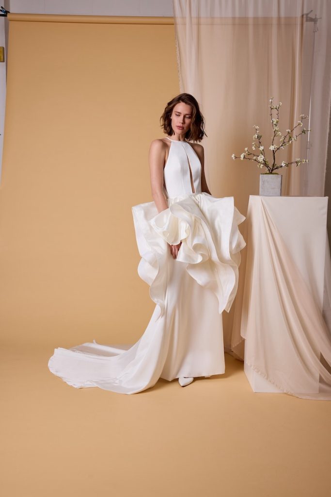 In questa foto, una modella che indossa un abito da sposa scivolato in satin triacetato con sopragonna della collezione sposa Nagae 2026