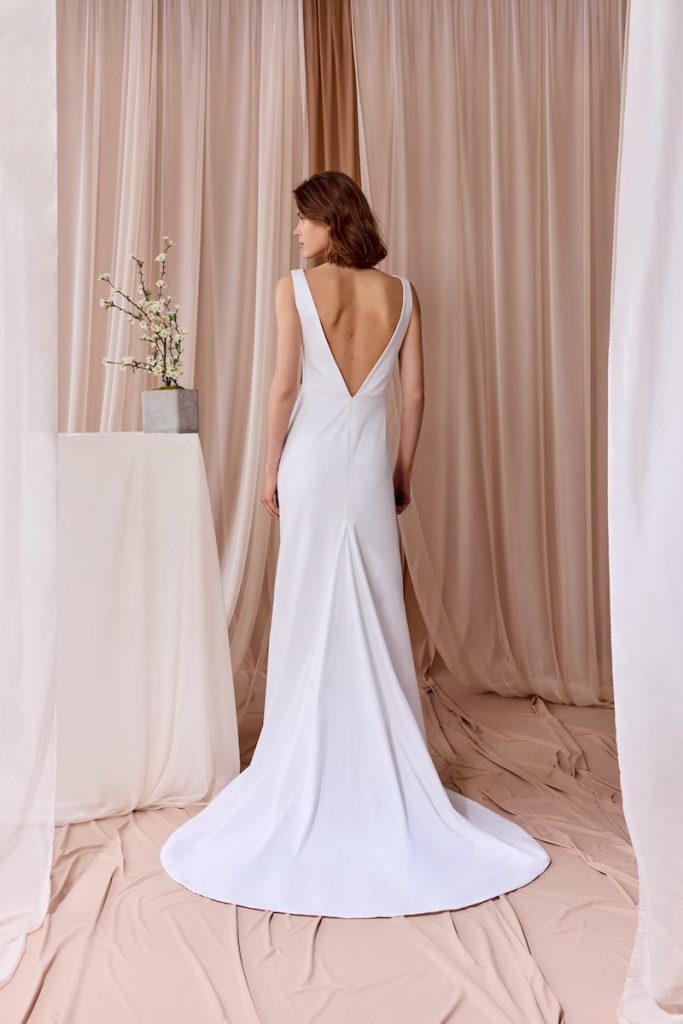 In questa foto, una modella inquadrata di spalle che indossa un abito da sposa scivolato in satin triacetato con scollatura posteriore della collezione sposa Nagae 2026