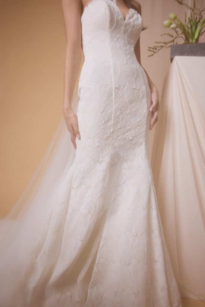 In questa foto, il dettaglio di una modella che indossa un abito da sposa a semi sirena in broccato della collezione sposa Nagae 2026