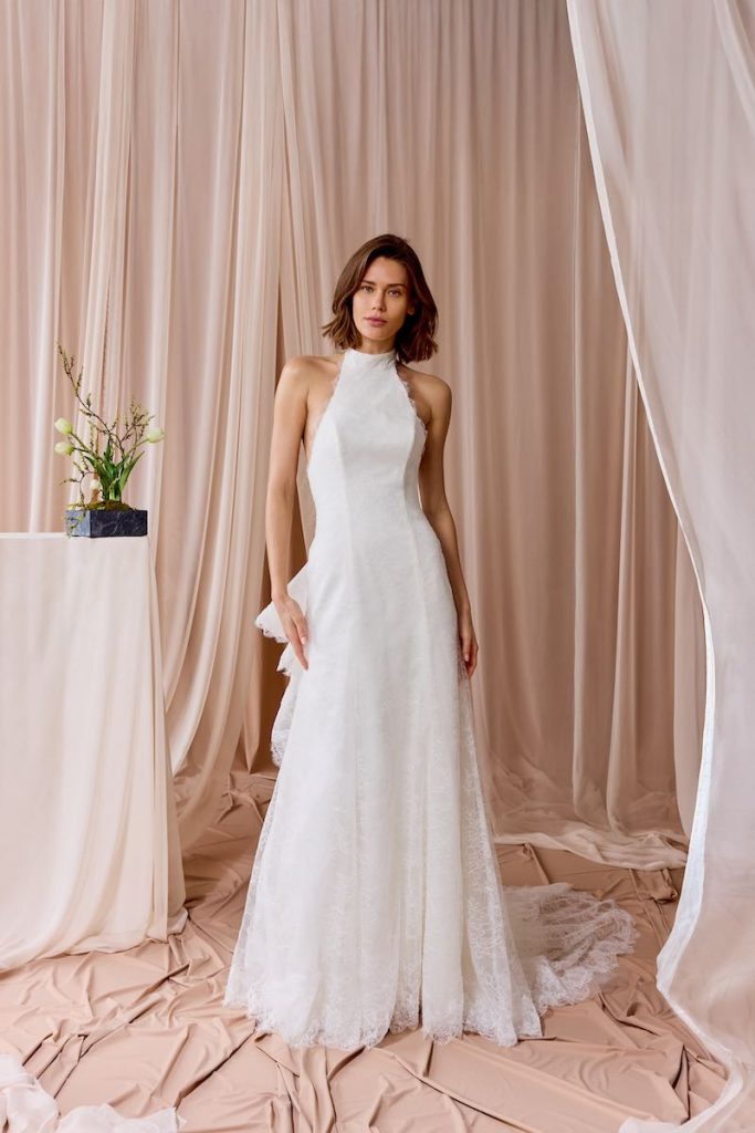 In questa foto, una modella indossa un abito da sposa scivolato in mikado e pizzo della collezione sposa Nagae 2026